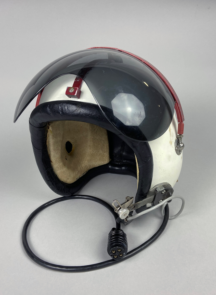Flyghjälm 111, vit med tonat visir. Separat mikrofon monterad på vänster sida. Brytkoppelanslutning för kommunikation. Utskjutande form vid öronen, insida med förstärkt inlägg av skinn med skumgummifyllning. Hjälmen är försedd med röd metallräls runt hjässan. Skodd nederkant i svart skinn.