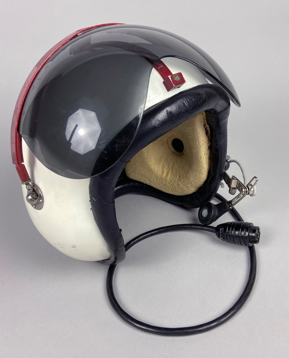 Flyghjälm 111, vit med tonat visir. Separat mikrofon monterad på vänster sida. Brytkoppelanslutning för kommunikation. Utskjutande form vid öronen, insida med förstärkt inlägg av skinn med skumgummifyllning. Hjälmen är försedd med röd metallräls runt hjässan. Skodd nederkant i svart skinn.