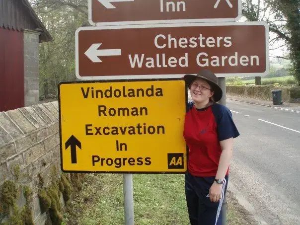 Arkeolog ved siden av et veiskilt til Vindolanda. 