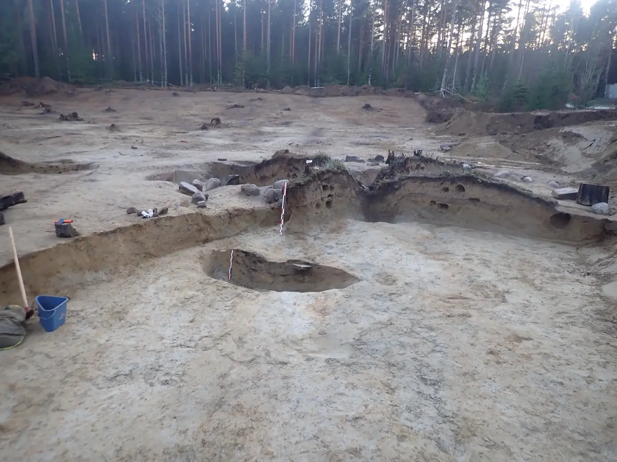 arkeologisk utgravning. Lys sand med mørke flekker etter forhistorisk aktivitet. 