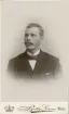 En man i mustasch, klädd i mörk kostym med stärkkrage och fluga.
Bröstbild, halvprofil. Ateljéfoto.
Kronolänsman Albert Bergstedt, Växjö. Morfar till givaren.