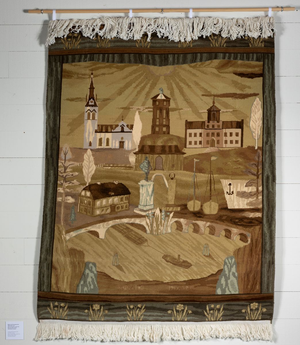 Vävd och knuten med motiv av kända byggnader och vyer i Karlstad såsom Stenbron, Domkyrkan, Gamla gymnasiet, Biskopsgården, Vattentornet på Herrhagen, statyn över Karl IX, flottningsbåt på Klarälven, hamnen, med mera.