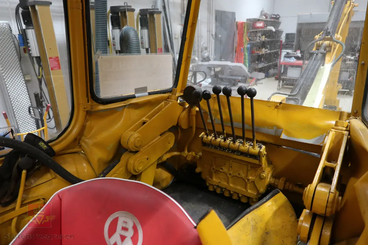 BM-Volvo T-400 traktor med Hymas type 4 graver. Gul, svart og rød traktorgraver lagd i hovedsak av metall, gummi og glass. Merket av produsentene. Dette er en jordbrukstraktor som er påmontert en graver, (gravemaskin), i bakkant. Graveren er hydraulisk drevet og har skuffe og to støtteben. Traktoren er 2-akslet har 6 hjul. To av hjulene er for å kunne bruke traktoren med halvbelter (belter følger med). Motoren er av typen D 913 fra BM, som betyr en tre sylindret firetakts diesel drevet type med slagvolum 2,5 liter. Motoren yter 47 (DIN) Hk. Motoren er bygd med basis fra en Perkins motor. Girkassen har innebygd reduksjons gir som gir åtte gir fremover og to gir bakover. Traktoren har 12 V elektrisk anlegg. Rødt sete merket med BM.
Følgende fulgte med maskinen:
- To skuffer og en hydraulikksentral samt to trekkstenger.
- Fire bilder/tegninger i glass og ramme.
- Regningsblokk.
- Innrammet avisutklipp.