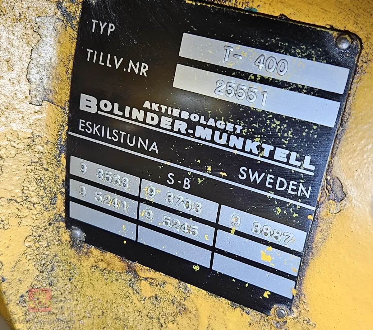 BM-Volvo T-400 traktor med Hymas type 4 graver. Gul, svart og rød traktorgraver lagd i hovedsak av metall, gummi og glass. Merket av produsentene. Dette er en jordbrukstraktor som er påmontert en graver, (gravemaskin), i bakkant. Graveren er hydraulisk drevet og har skuffe og to støtteben. Traktoren er 2-akslet har 6 hjul. To av hjulene er for å kunne bruke traktoren med halvbelter (belter følger med). Motoren er av typen D 913 fra BM, som betyr en tre sylindret firetakts diesel drevet type med slagvolum 2,5 liter. Motoren yter 47 (DIN) Hk. Motoren er bygd med basis fra en Perkins motor. Girkassen har innebygd reduksjons gir som gir åtte gir fremover og to gir bakover. Traktoren har 12 V elektrisk anlegg. Rødt sete merket med BM.
Følgende fulgte med maskinen:
- To skuffer og en hydraulikksentral samt to trekkstenger.
- Fire bilder/tegninger i glass og ramme.
- Regningsblokk.
- Innrammet avisutklipp.