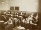 En skolklass med flickor och pojkar i ett klassrum.
Klass 1, Flickskolan (?), Växjö, 1907. 
I bakersta raden, 6:e fr. v. syns Margareta Bergstedt.