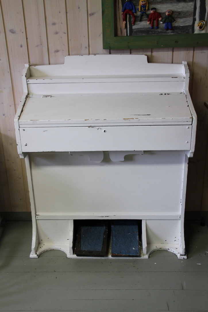 Husorgelet er i hvitmalt tre. Det er ikke i brukbar stand.
