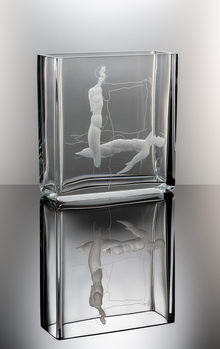 Formgivare: Olle Alberius. Gravör: Anders Svensson. Vas, Expo. Rektangulär, tjockväggig vas med graverat motiv föreställande en kvinna och man utförande en formation.