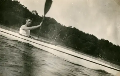 Fotografi taget från en tältplats. 
Vi ser hur Åke Börjesson paddlar sig fram.
Oklart när fotografiet är taget.