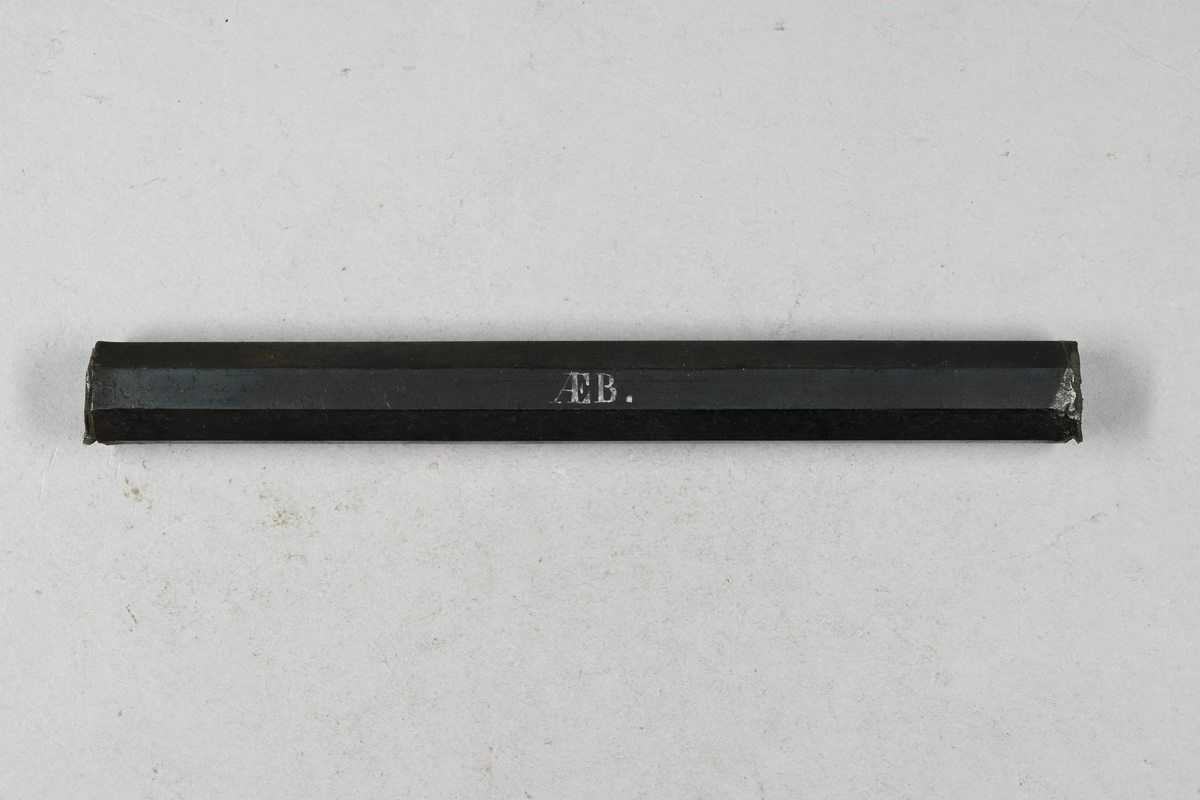 Prov på uträckt brännstål från Munkfors bruk. Två tillhörande lappar med notering: "725. Uträckt brännstål från Munkfors. 1867." Märkning på provet med notering: "AEB."