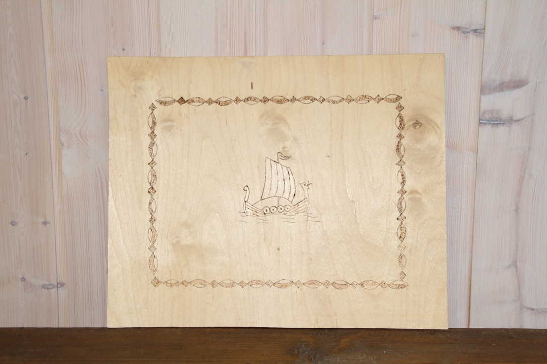 Finerplate, ca 30cm x 30 cm, med brent dekor, dekoren er et vikingskip med bord 