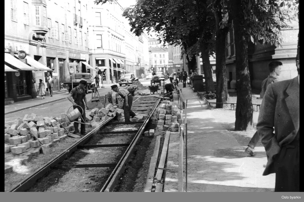 Gate / sporarbeide i Kristian Augusts gate mot Universitetsgata. Arbeidere, gatesten. Butikker.