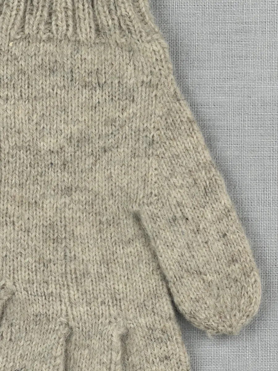 En stickad fingervante, med mudd i 2-2 resår (2 räta och 2 aviga maskor) och vante mönstrad med aviga maskor på slätstickning, av 2-trådigt ullgarn.