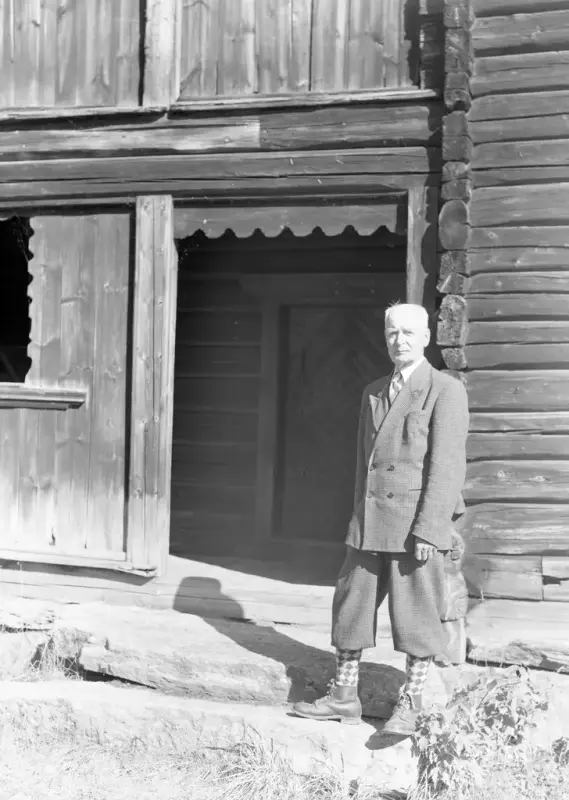 Mann med eplenikkers stående foran museumshus fra Prestøy