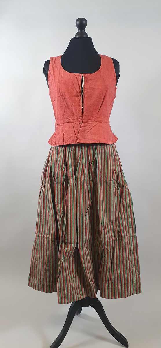 Rødt liv av lin, med seks skjøter (flak) somskår ut fra livlinjen. Metallhemper i åpningen foran. Livet er fôret med ubleket bomull. Brodert navn på innsiden av forstykket.