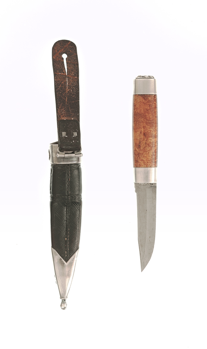 Staskniv frå knivmakar Hans Sjåberg.

Kniven ser ut til å ha skaft av bjørk, med enkle sylvholkar. Glibb forma som liggande bikkje.

Slira er av lêr og har pauta rankemønster. Holk og doppsko i sylv med filigranarbeid.
