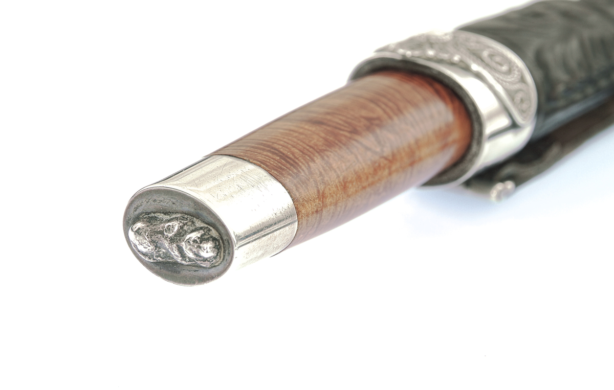 Staskniv frå knivmakar Hans Sjåberg.

Kniven har skaft av treverk med enkle sylvholkar. Glibb forma som liggande bikkje.

Slira er av lêr og har pauta rankemønster. Holk og doppsko i sylv med filigranarbeid.
