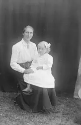 Portrett av en kvinne og en jente. Kvinnen sitter på en stol