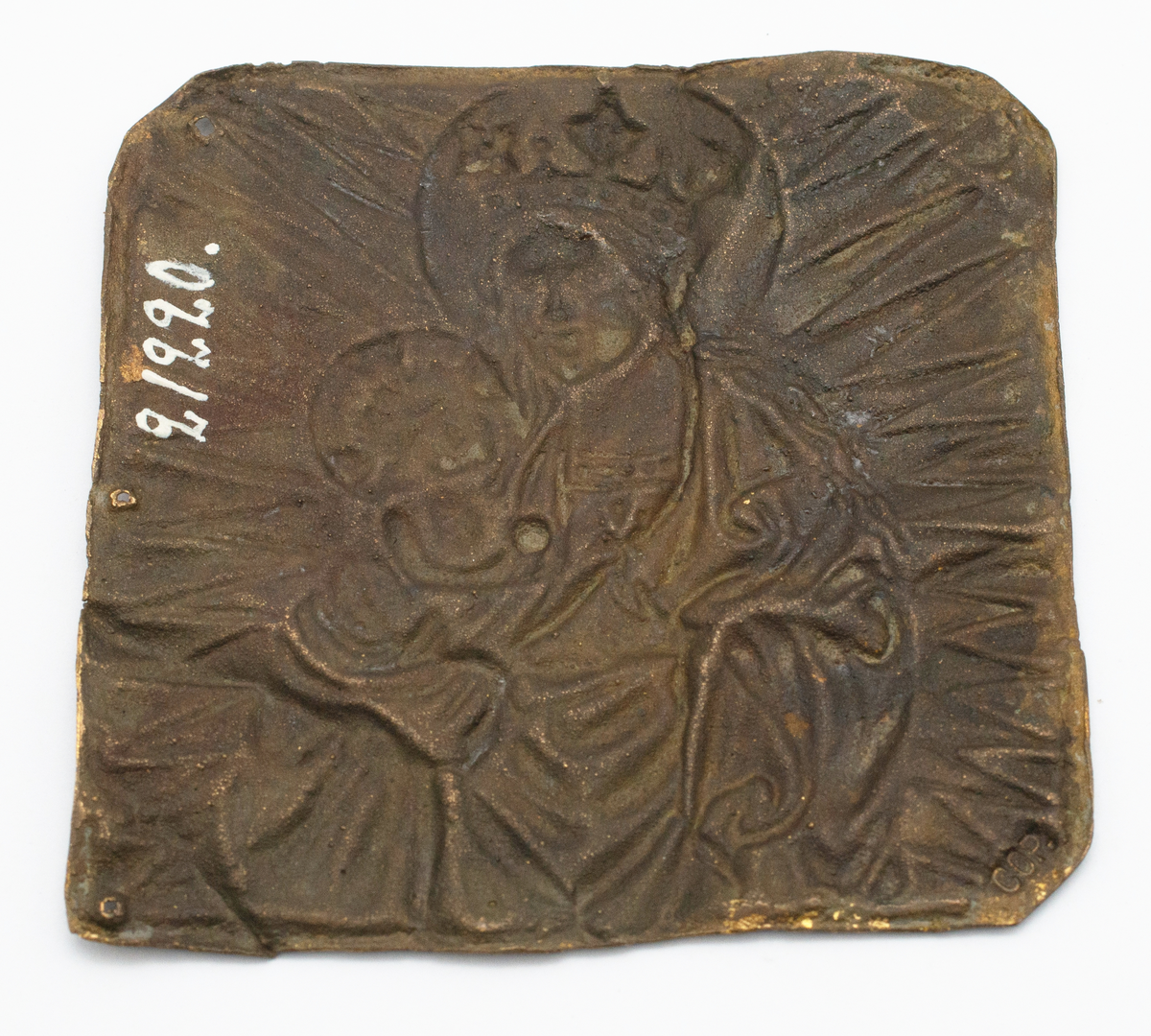 Förgylld kopparplåt med pressad bild av madonnan och barnet omgiven av en strålgloria. Tre hål i plåtens högra sida.