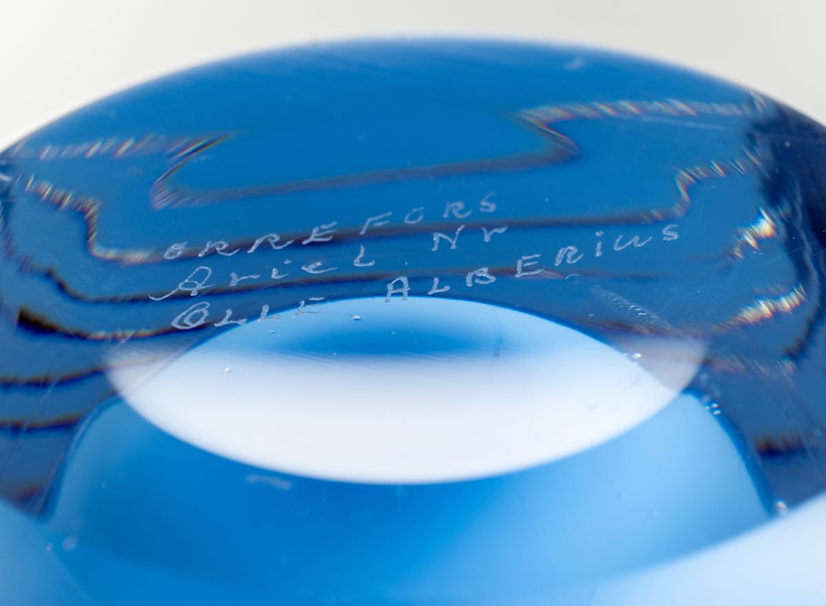 Arielvas, tjockväggig. Cylindrisk form. Ametistlila och delftblå färgton med abstrakt luftmönster i form av kulor och linjer.
Formgivare: Olle Alberius.