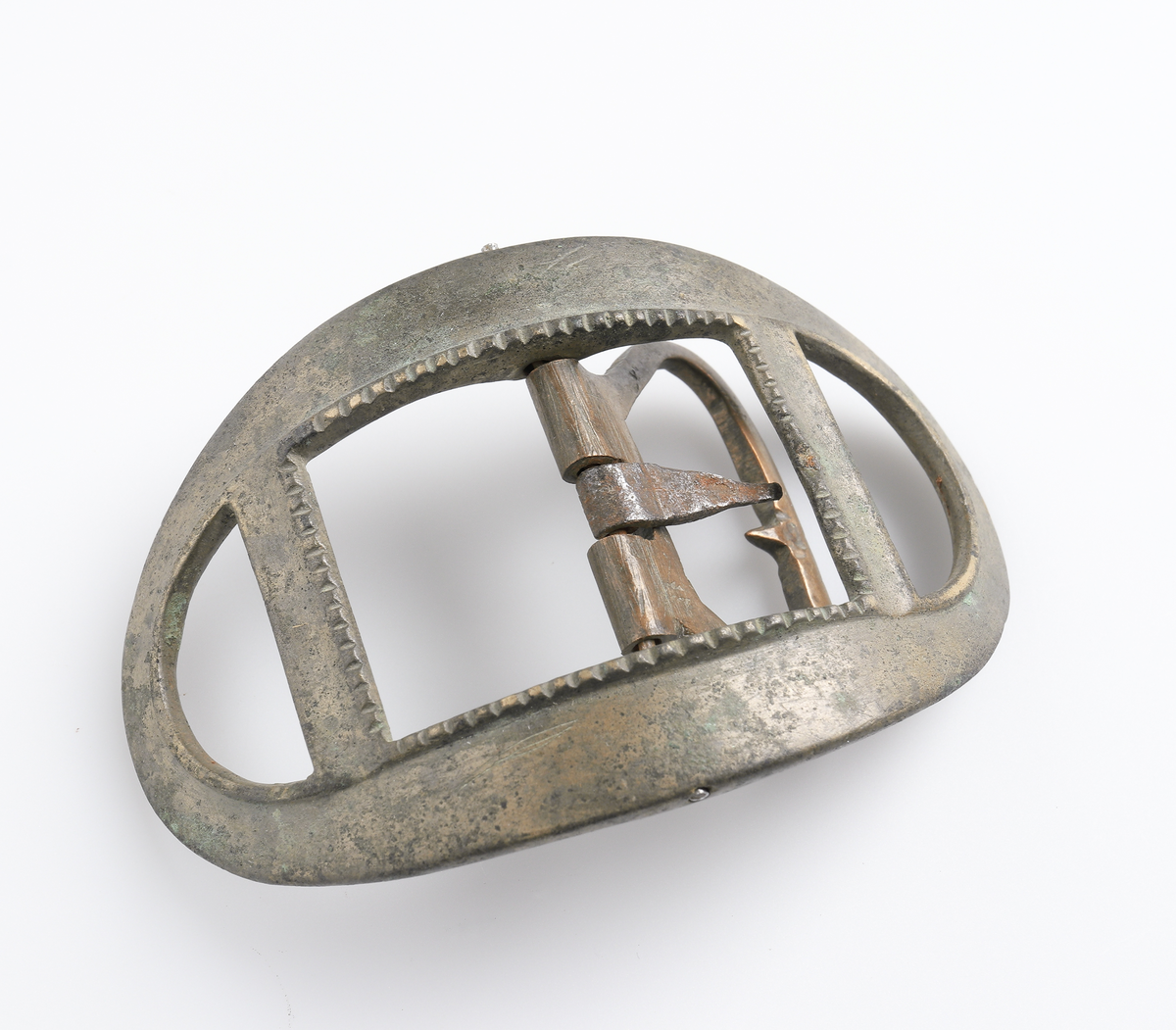 Knäspänne av järn. Oval form, något välvd. Genombruten ram i ytterkanterna, dekor på inre kant.

Inskrivet i huvudbok 1886.