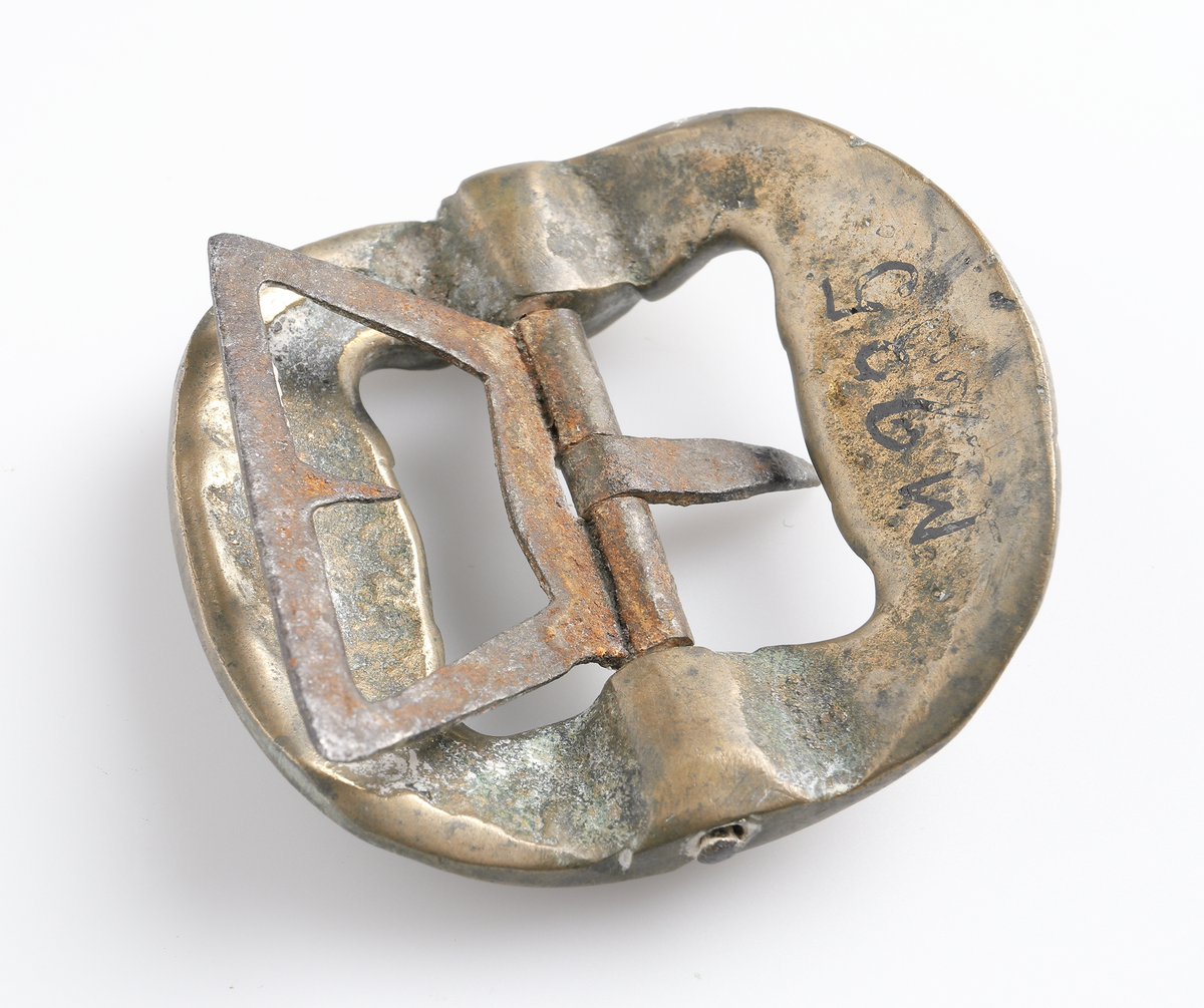 Knäspänne av gjuten gulmetall, med nål och fäste av järn. Avrundad fyrkantig form, något välvd.

Inskrivet i huvudbok 1886.