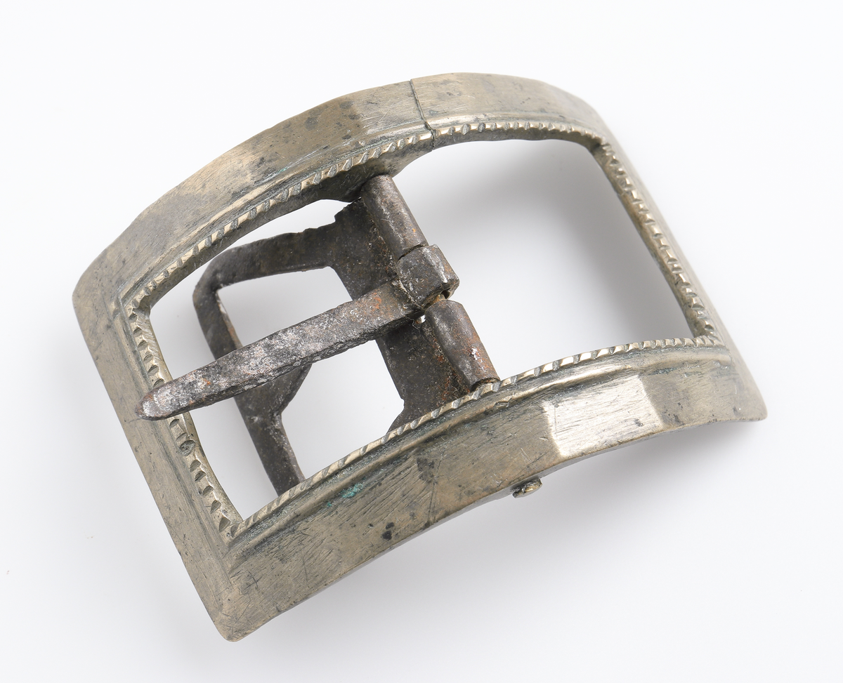 Knäspänne av järn. Rektangulär form, något välvd, med dekor på inre kant.

Inskrivet i huvudbok 1886.