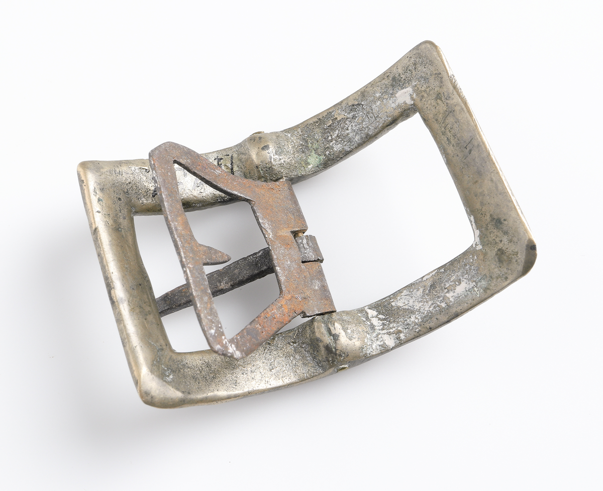 Knäspänne av järn. Rektangulär form, något välvd, med dekor på inre kant.

Inskrivet i huvudbok 1886.