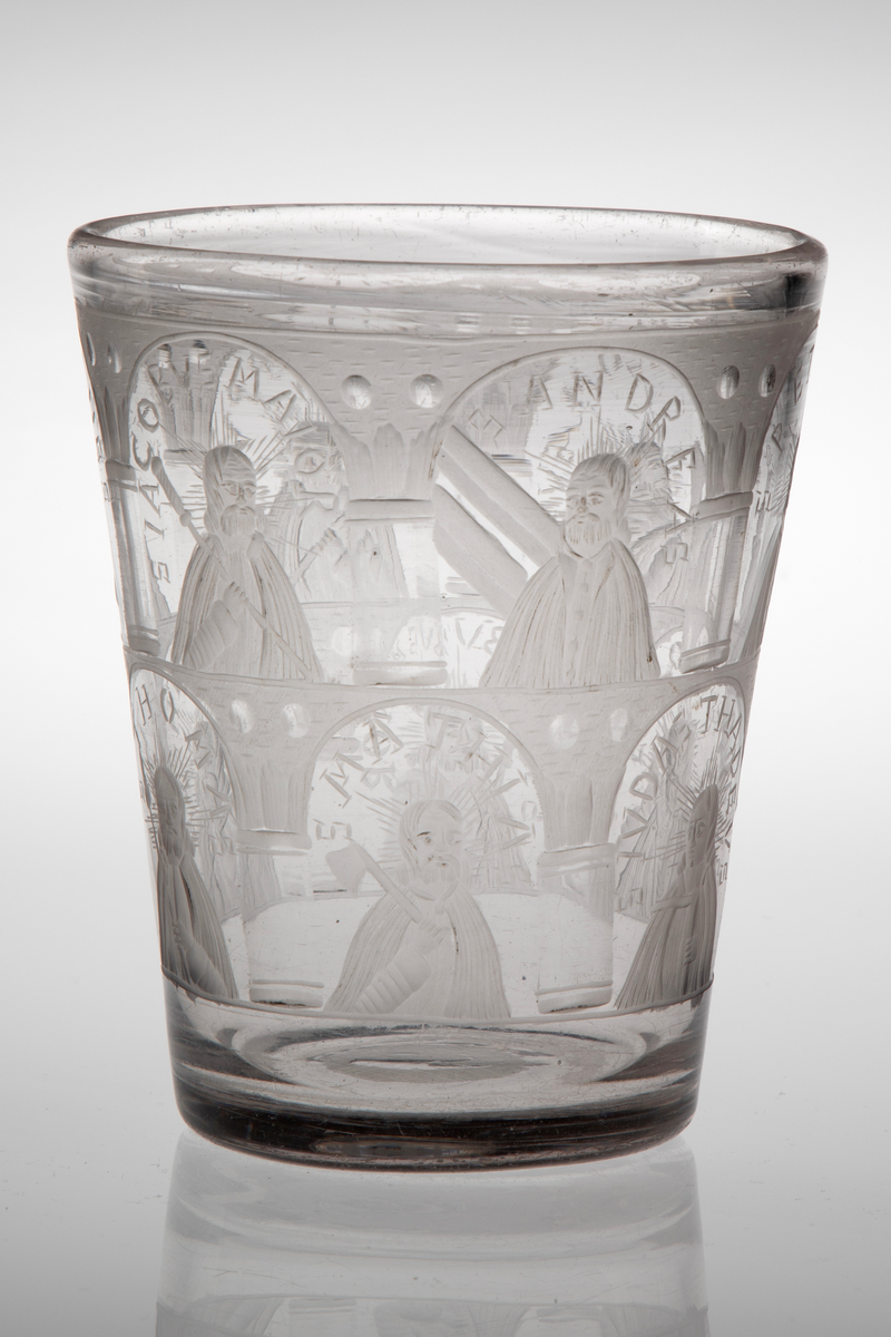 Tilnærmet sylinderformet beger i tykt klart glass med svakt koniske vegger. Yttersiden er dekorert med sliping og gravering, i form av arkadebuer i to etasjer som inndeler begerets overflate i tolv nisjer. I hver nisje er det fremstilt en av de tolv apostlene, som holder hver sitt ikonografiske attributt. Rester av puntemerke under bunnen. 

I øvre rekke:
1) Peter med nøkkel, omgitt av innskriften: "S P E T R V S".
2) Bartolomeus med sverd, omgitt av innskriften: "S B A R T H O L O M Æ V S".
3) Filip med kors, omgitt av innskriften: "S P H I L I P P V S".
4) Johannes med beger, omgitt av innskriften: "S I O H A N N E S".
5) Jakob den eldre med pilgrimsstav, omgitt av innskriften: "S I A C O B V S M A I O R".
6) Andreas med to diagonale planker på høyre side, antagelig en henvisning til det x-formede korset, omgitt av innskriften: "S A N D R E A S".

I nedre rekke: 
1) Matteus med hellebard, omgitt av innskriften: "S M A T H E V S".
2) Thomas med lanse, omgitt av innskriften: " S T H O M A S".
3) Mattias med øks, omgitt av innskriften: "S M A T H I A S".
4) Judas Taddeus med knortekjepp, omgitt av innskriften: "S I V D A S T H A DE V S".
5) Simon med sag, omgitt av innskriften: "S S I M O N I S"
6) Jakob den yngre med pilegrimsstav, omgitt av innskriften "S I A C O B V S M I N O R".