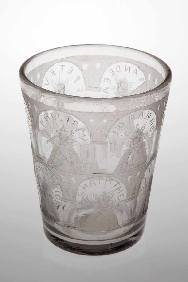 Tilnærmet sylinderformet beger i tykt klart glass med svakt koniske vegger. Yttersiden er dekorert med sliping og gravering, i form av arkadebuer i to etasjer som inndeler begerets overflate i tolv nisjer. I hver nisje er det fremstilt en av de tolv apostlene, som holder hver sitt ikonografiske attributt. Rester av puntemerke under bunnen. 

I øvre rekke:
1) Peter med nøkkel, omgitt av innskriften: "S P E T R V S".
2) Bartolomeus med sverd, omgitt av innskriften: "S B A R T H O L O M Æ V S".
3) Filip med kors, omgitt av innskriften: "S P H I L I P P V S".
4) Johannes med beger, omgitt av innskriften: "S I O H A N N E S".
5) Jakob den eldre med pilgrimsstav, omgitt av innskriften: "S I A C O B V S M A I O R".
6) Andreas med to diagonale planker på høyre side, antagelig en henvisning til det x-formede korset, omgitt av innskriften: "S A N D R E A S".

I nedre rekke: 
1) Matteus med hellebard, omgitt av innskriften: "S M A T H E V S".
2) Thomas med lanse, omgitt av innskriften: " S T H O M A S".
3) Mattias med øks, omgitt av innskriften: "S M A T H I A S".
4) Judas Taddeus med knortekjepp, omgitt av innskriften: "S I V D A S T H A DE V S".
5) Simon med sag, omgitt av innskriften: "S S I M O N I S"
6) Jakob den yngre med pilegrimsstav, omgitt av innskriften "S I A C O B V S M I N O R".