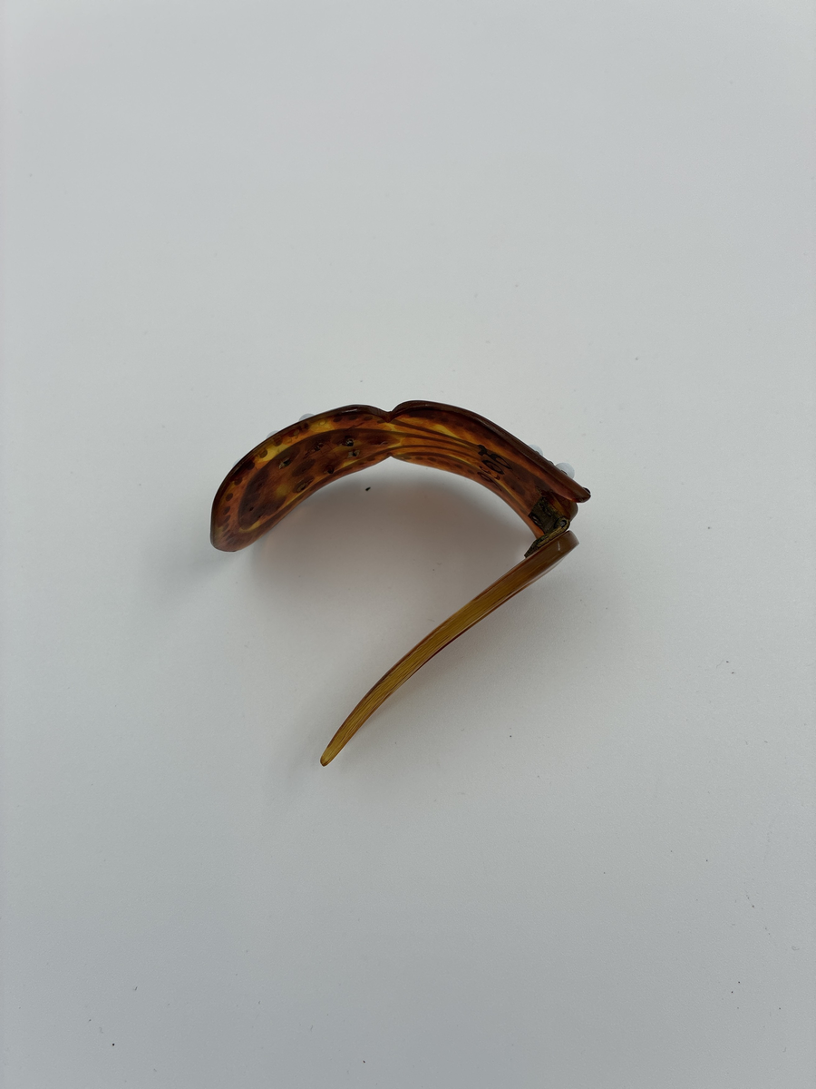 Hårkam av sköldpadd med limmade pärlor i vitt och svart.