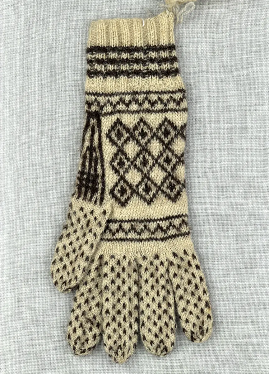 Ett par stickade fingervantar, med randig mudd i 2-2 resår (2 räta och 2 aviga maskor) och mönsterstickad vante i slätstickning, av 2-trådigt ullgarn.

