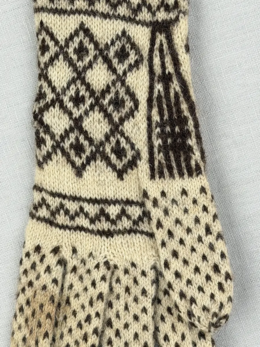 Ett par stickade fingervantar, med randig mudd i 2-2 resår (2 räta och 2 aviga maskor) och mönsterstickad vante i slätstickning, av 2-trådigt ullgarn.
