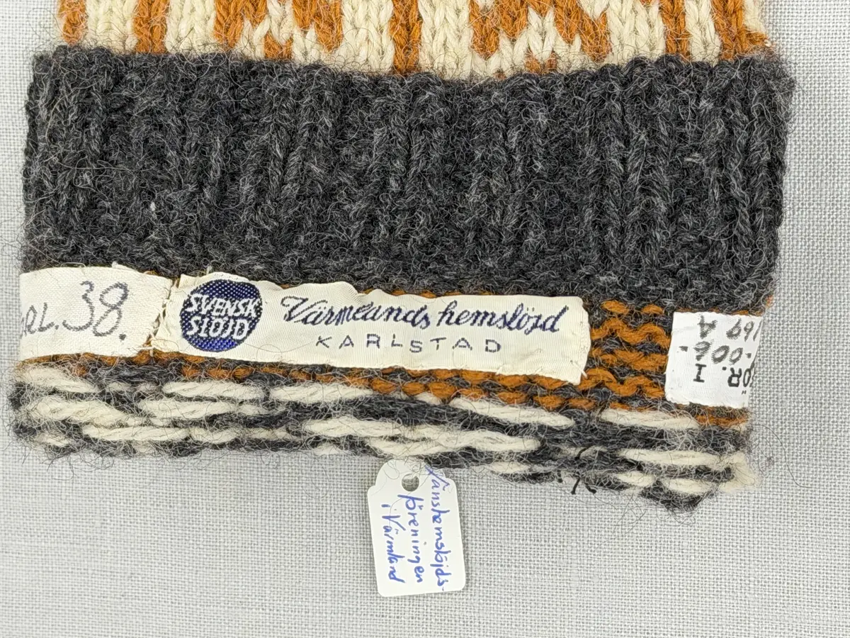 En stickad socka, med mudd i 2-2 resår (2 räta och2 aviga maskor) samt mönsterstickad fot och skaft i slätstickning, av 3-trådigt ullgarn.