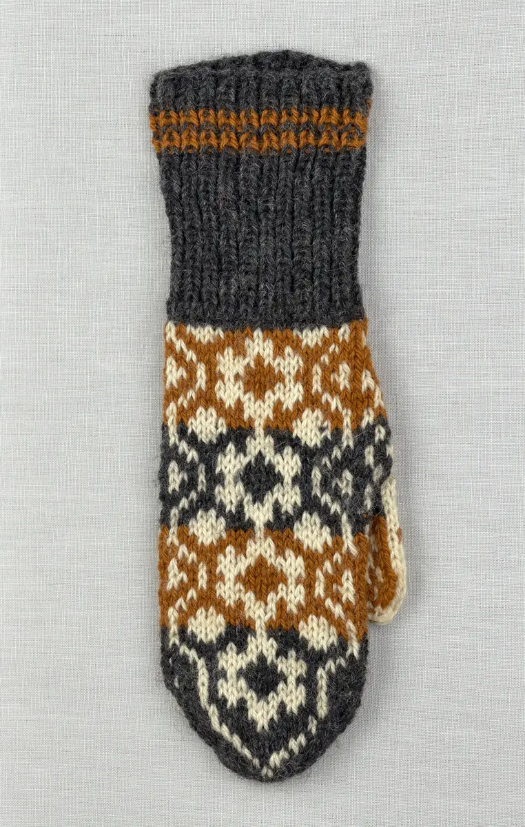 En stickad tumvante, med randig mudd i 1-1 resår (1 rät och 1 avig maska) och mönsterstickad vante i slätstickning, av 3-trådigt ullgarn.