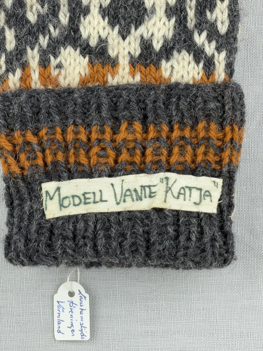 En stickad tumvante, med randig mudd i 1-1 resår (1 rät och 1 avig maska) och mönsterstickad vante i slätstickning, av 3-trådigt ullgarn.