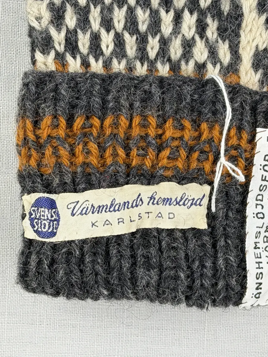 En stickad tumvante, med randig mudd i 1-1 resår (1 rät och 1 avig maska) och mönsterstickad vante i slätstickning, av 3-trådigt ullgarn.