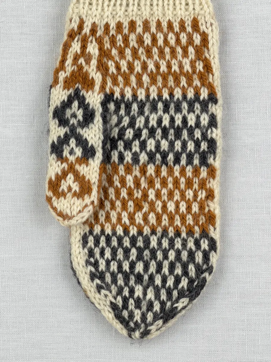 En stickad tumvante, med randig mudd i 1-1 resår (1 rät och 1 avig maska) och mönsterstickad vante i slätstickning, av 3-trådigt ullgarn.