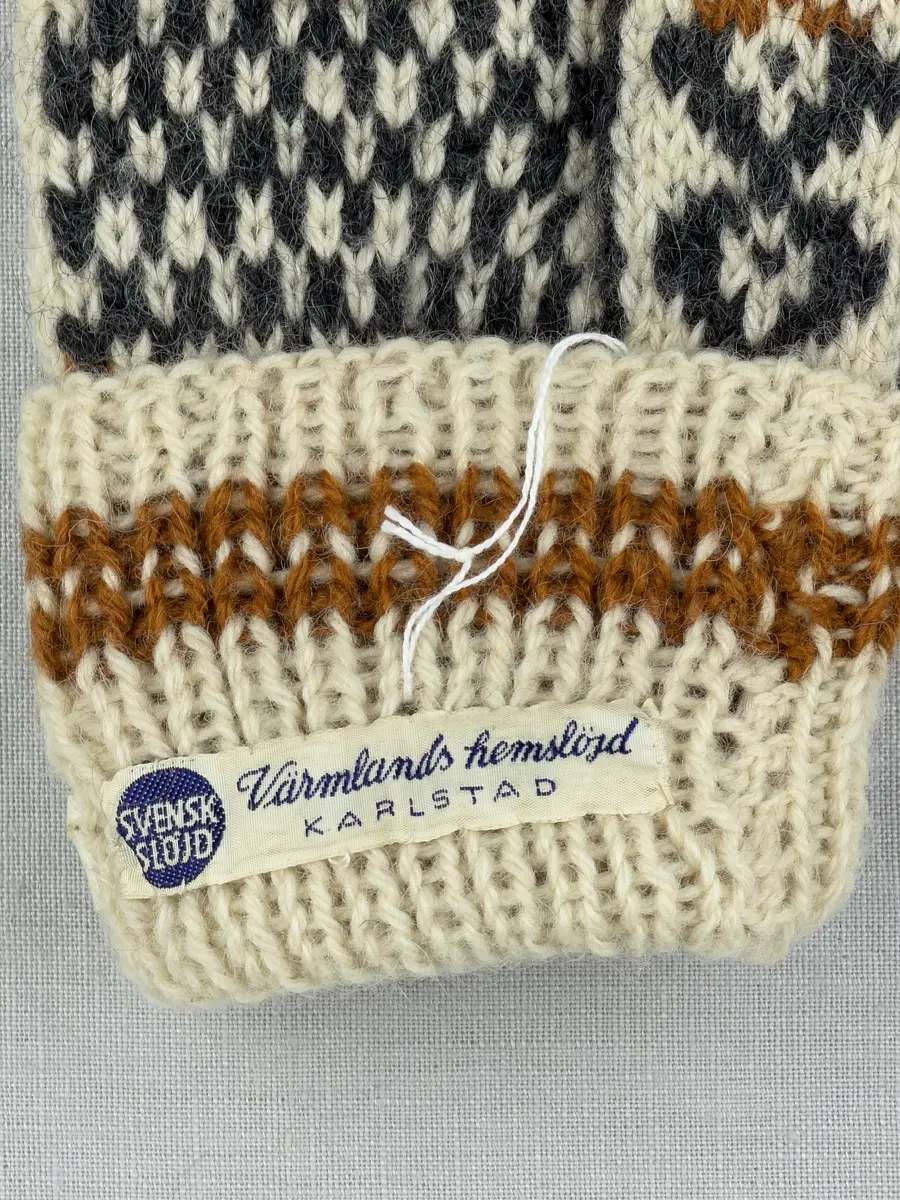 En stickad tumvante, med randig mudd i 1-1 resår (1 rät och 1 avig maska) och mönsterstickad vante i slätstickning, av 3-trådigt ullgarn.