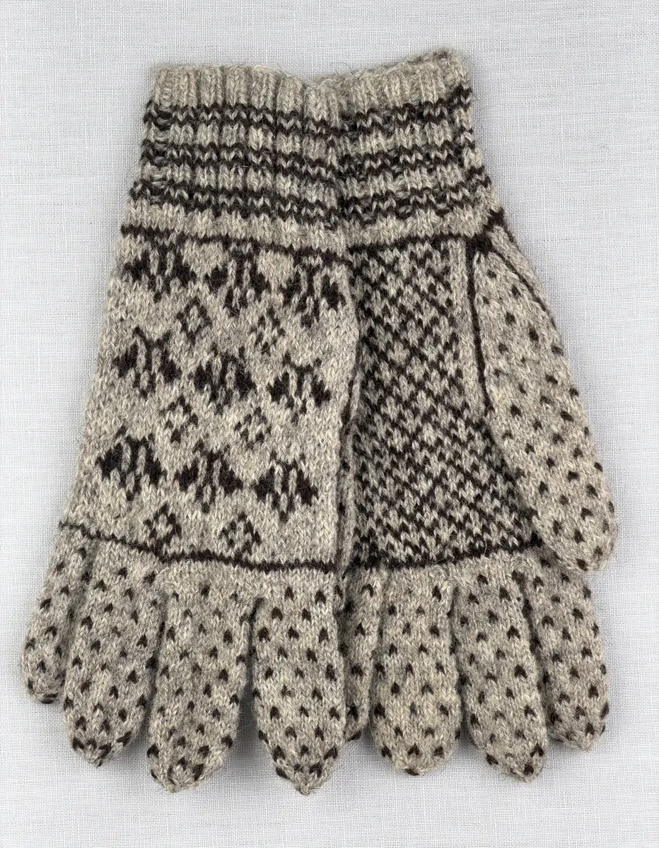 En stickad fingervante, med randig mudd i 2-2 resår (2 räta och 2 aviga maskor) och mönsterstickad vante i slätstickning, av 2-trådigt ullgarn.