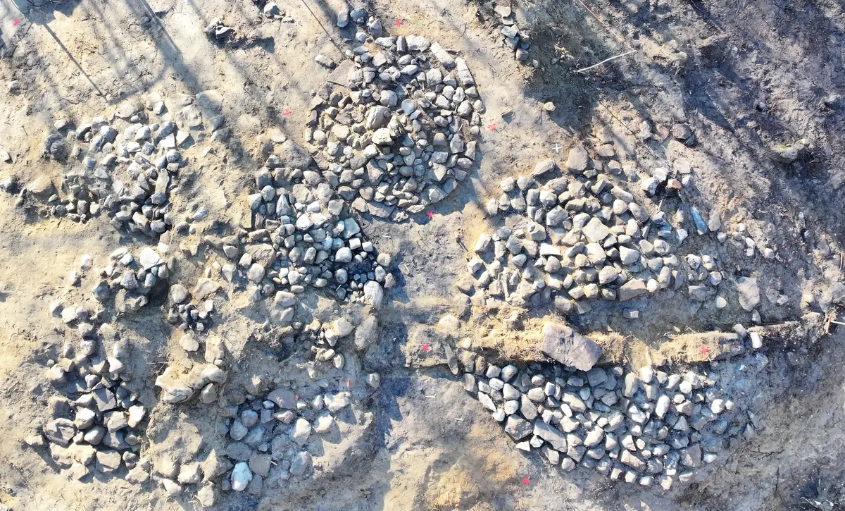 Gravhögar i sten med jord runtom tagen uppifrån.