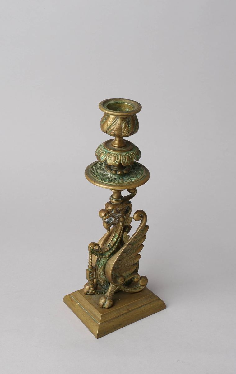 På rektangulær profilkantet fot står en griff (bevinget, ormekropp med løvehode), som på hodet bærer lyspipe og dryppskål. Pipen har akantusblader i lavt relieff, dryppskålen har et litt dypere arabeskaktig relieff. Griffen er rik på detaljer.
