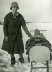 Vinterbilde. En kvinne med et liten barn i en barnevogn. Kan