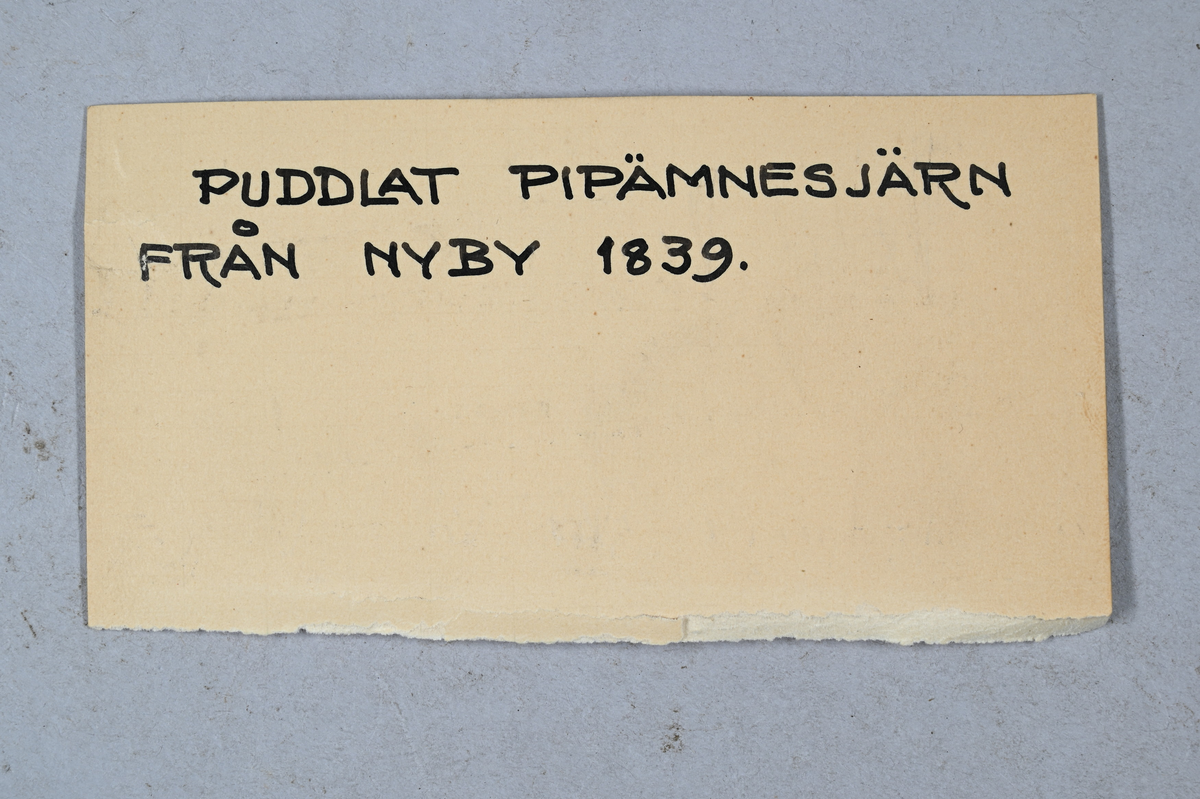 Prov på puddlat pipämnesjärn från Nyby, tillverkat år 1839. Tillhörande lapp med samma notering.