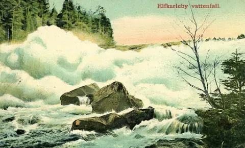 Kolorerad bild av Älvkarleby vattenfall, Uppland. Text baksida kort: "Hjärtlig gratulation på Erika dagen önskas av syster Johanna. Vi hava alla hälsan och mår bra. Många hälsningar medföljer till eder, litet för sent men bättre sent än aldrig".