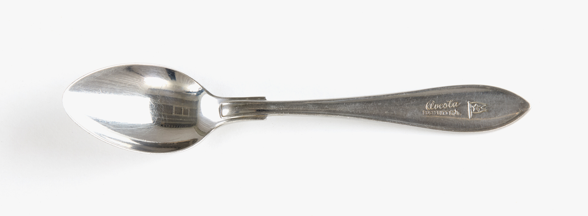 Formstansad sked i rostfritt stål med lätt spetsig skedskål och spetsavslutat skaft. Skaftet stämplat "Avesta rostfritt stål" samt Johnson lines logotyp. Undertill stämplad "rostfri".