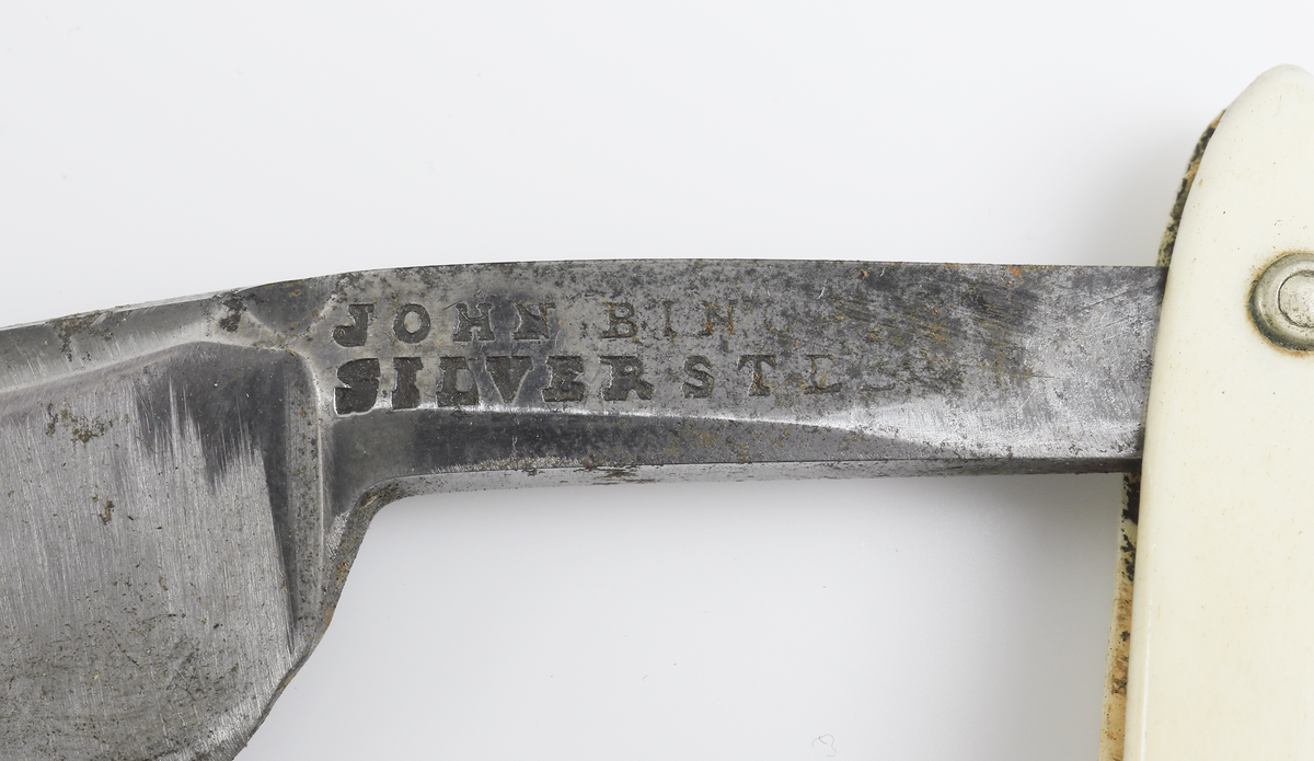 Kilformigt läderetui, kantat med sydda skinnband. Etuiet har fyra tygfodrade fickor, avsedda för rakknivar. Fickorna täcks av ett lock som har låsts av ett band. Två rakknivar finns kvar. De är försedda med blanka stålslipade, något böjda knivblad som kan fällas in i skaften. Skaften är tillverkade av sammannitade benskenor. 
Etuiet är enligt uppgift tillverkat av prosten Caspar Cederschiöld. På den ena kniven står instämplat J.E "Town Made" (kniv 1). Den andra är tillverkad av John Bing "Silversteel" (kniv 2) . Båda knivarna är tillverkade i England i början eller mitten av 1800-talet. 

Inskrivet i huvudbok år 1892-1900.