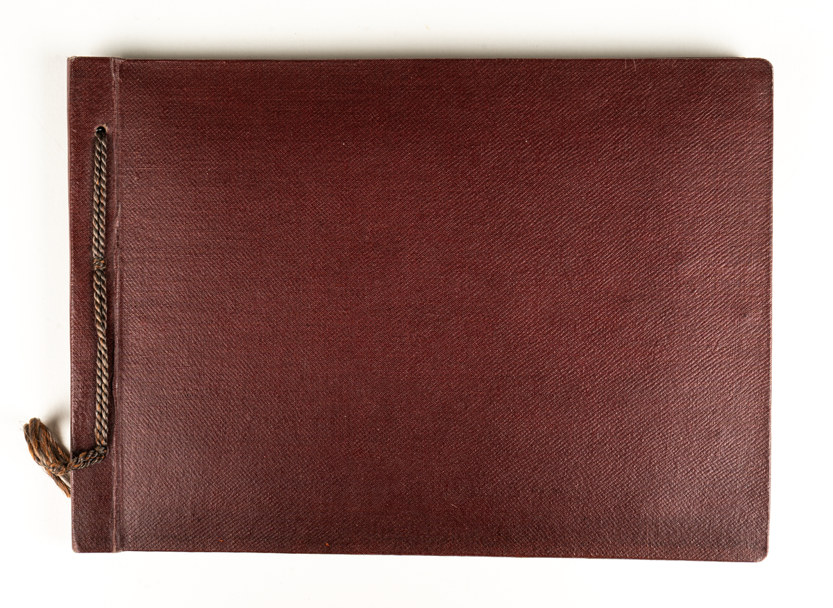 Fotoalbum, mörkröda pärmar med en mörkrödd snodd i ryggen. Innehåller foton från Heliga Trefaldighetskyrkan och Soldatkyrkan i Gävle.