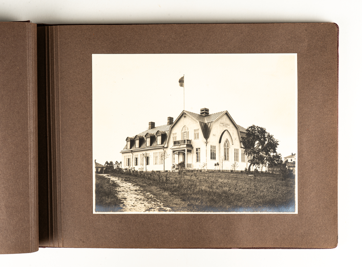 Fotoalbum, mörkröda pärmar med en mörkrödd snodd i ryggen. Innehåller foton från Heliga Trefaldighetskyrkan och Soldatkyrkan i Gävle.