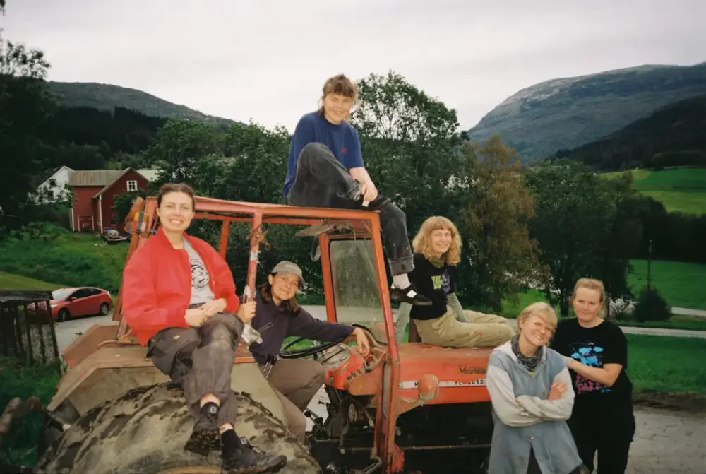 seks damer der nokre står ved sida av, eller sit på, ein raud traktor