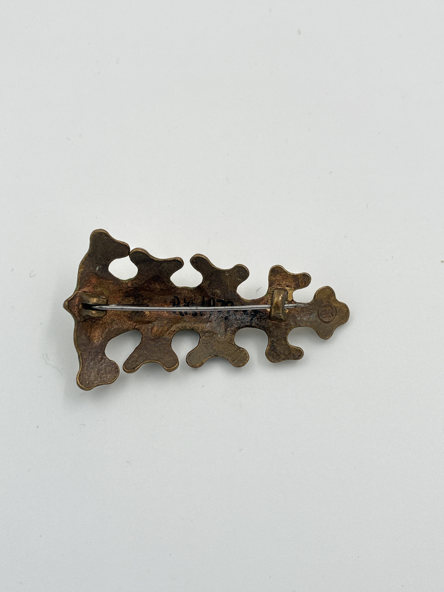 Brosch av brons. Från det finska smyckesmärket Kalevala Korus serie Oksa. Insidan stämplad KK i en cirkel.